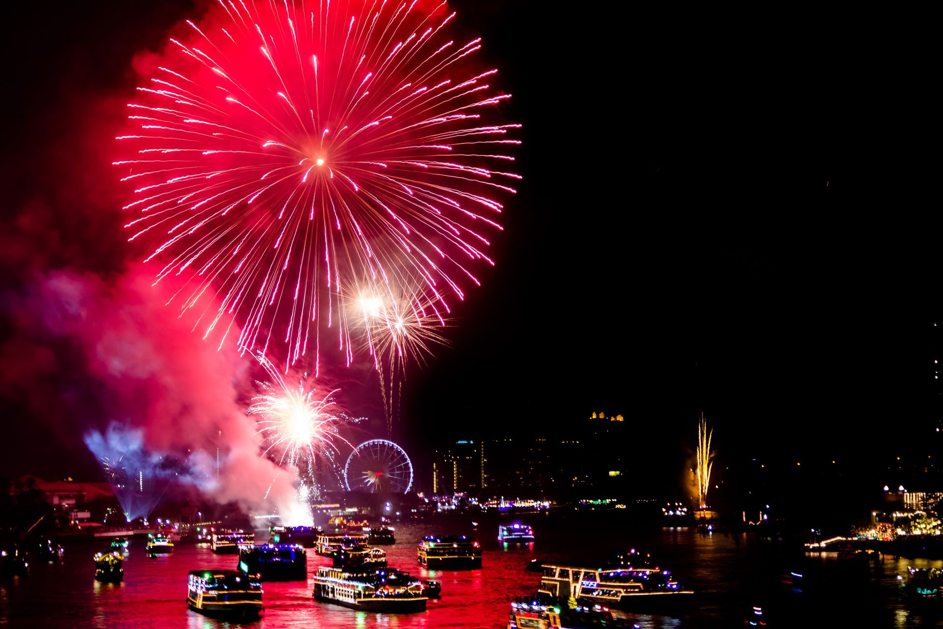 A fireworks display over a body of water with boats in the foreground