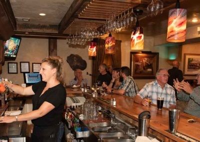 A group of people are sitting at a bar in a restaurant.