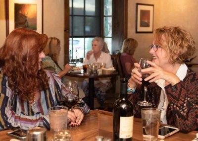 Two women are sitting at a table drinking wine.