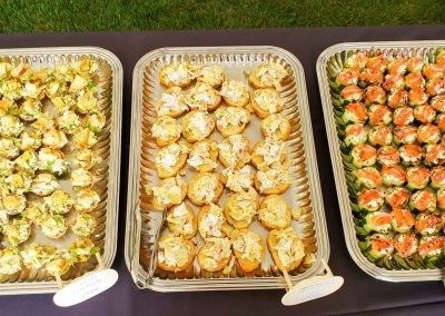 Three trays of food are sitting on a table.