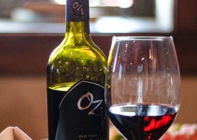 A bottle of wine and a glass of wine are on a table.