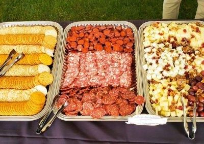 Three trays filled with different types of food on a table.