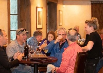 A group of people are sitting at tables in a restaurant drinking wine.