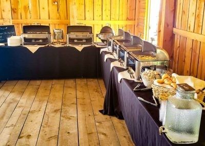 A buffet line is set up in a wooden barn.
