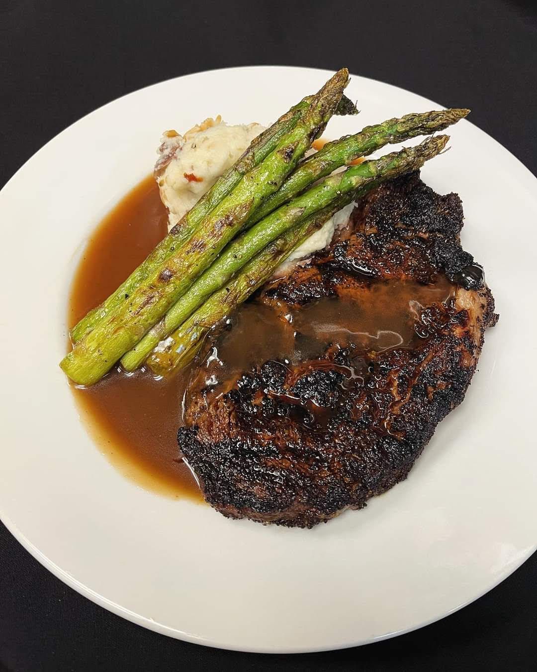 A White Plate Topped with A Steak , Mashed Potatoes and Asparagus.