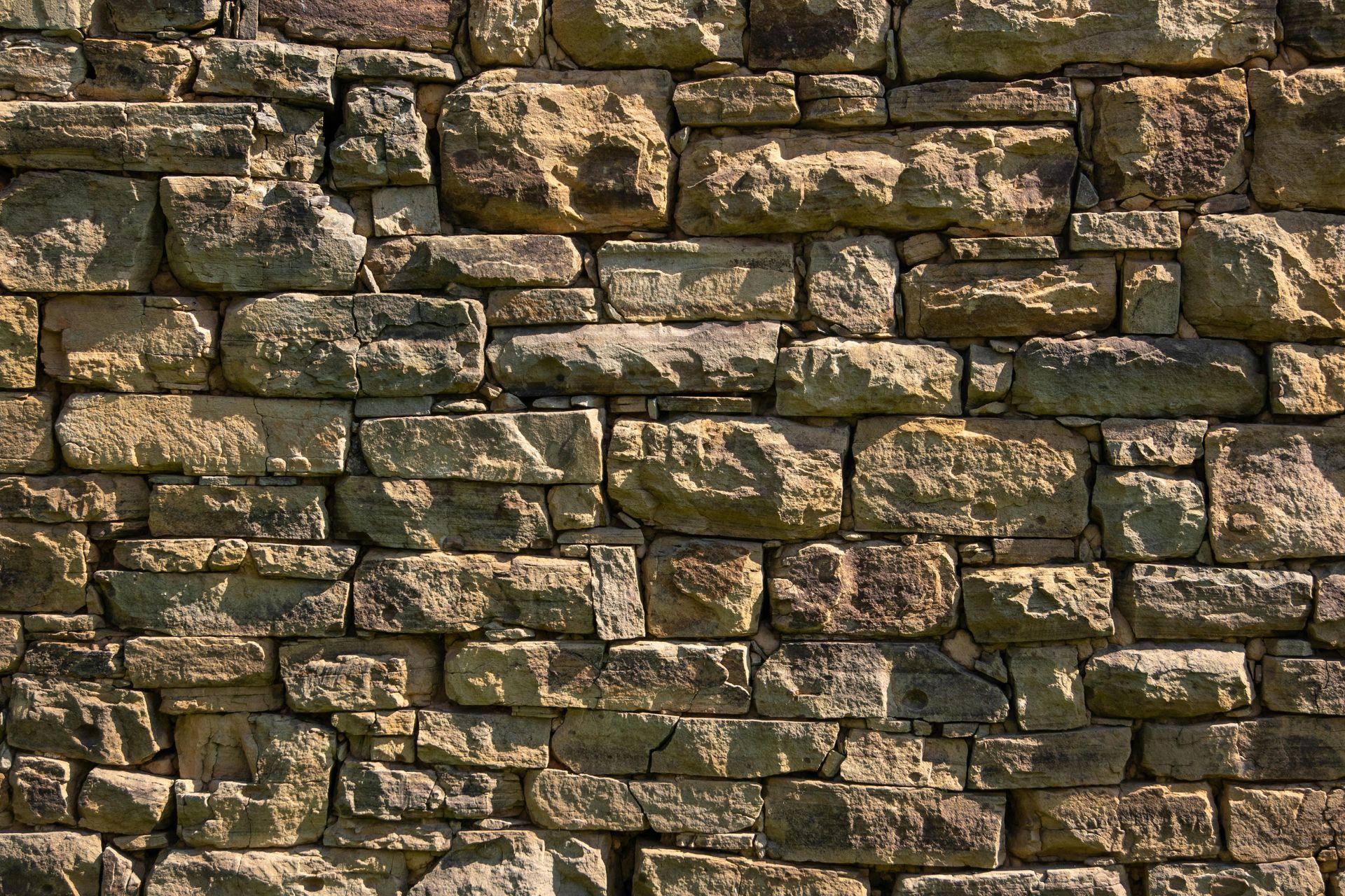 Close-up of a weathered stone wall with stacked brown and gray bricks.