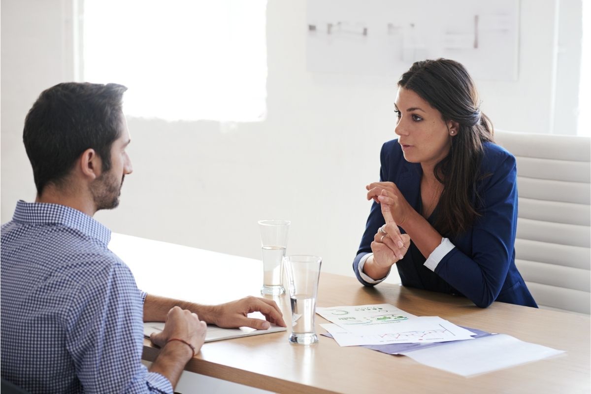 A man and a woman are sitting at a table across from each other having a conversation.