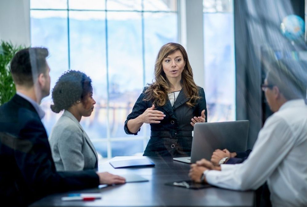 A group of business people are sitting around a conference table having a meeting.