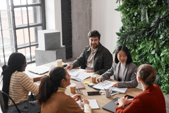 A group of people are sitting around a table having a meeting.
