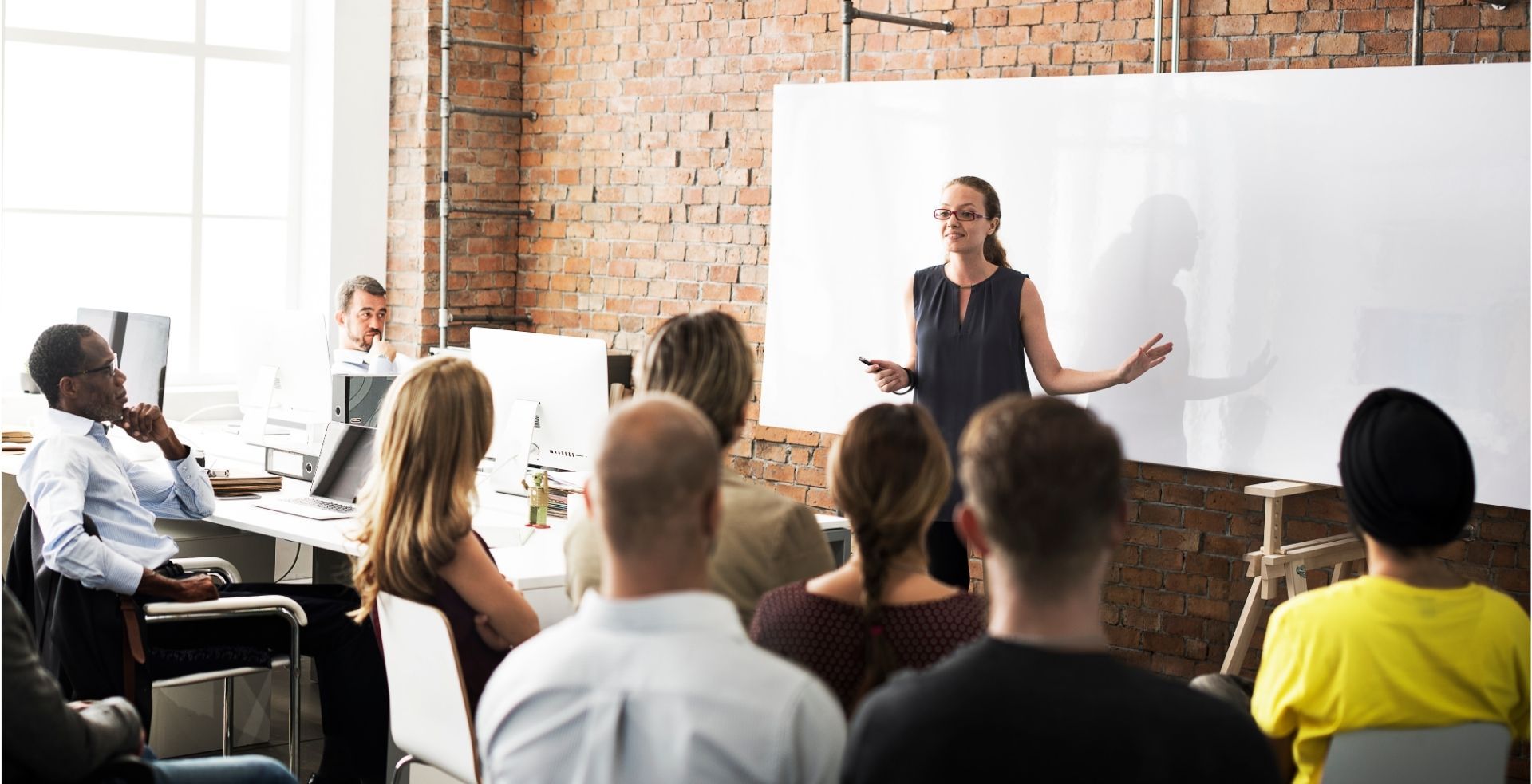 A woman is giving a presentation to a group of people in a room.