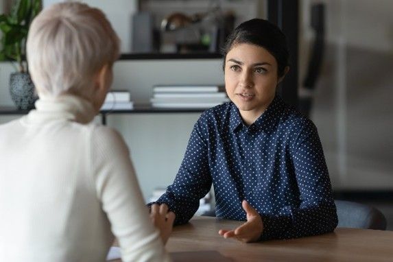 Two women are sitting at a table having a conversation.