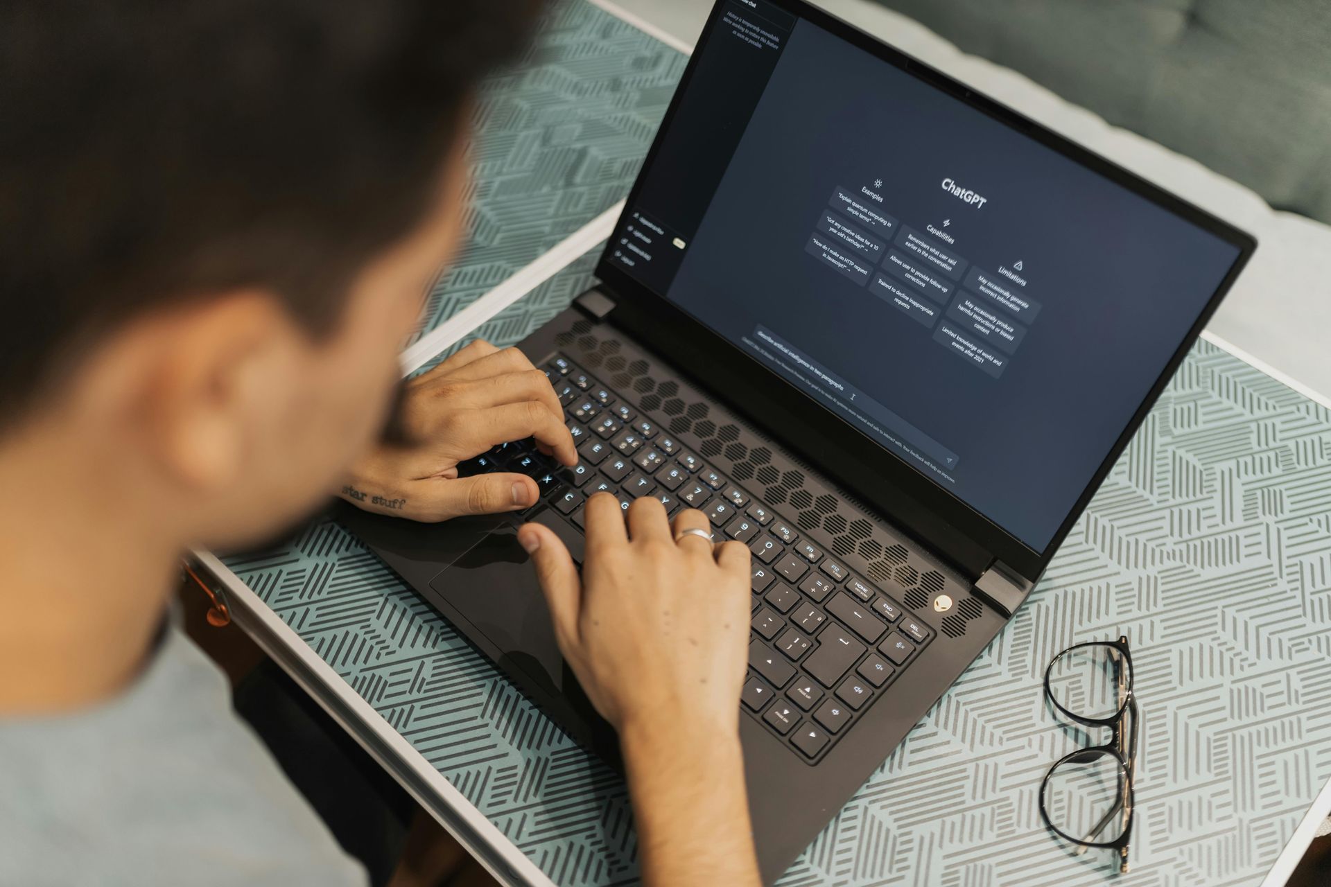 A man is typing on a laptop computer on a table.