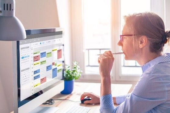 A woman is sitting at a desk looking at a computer screen.