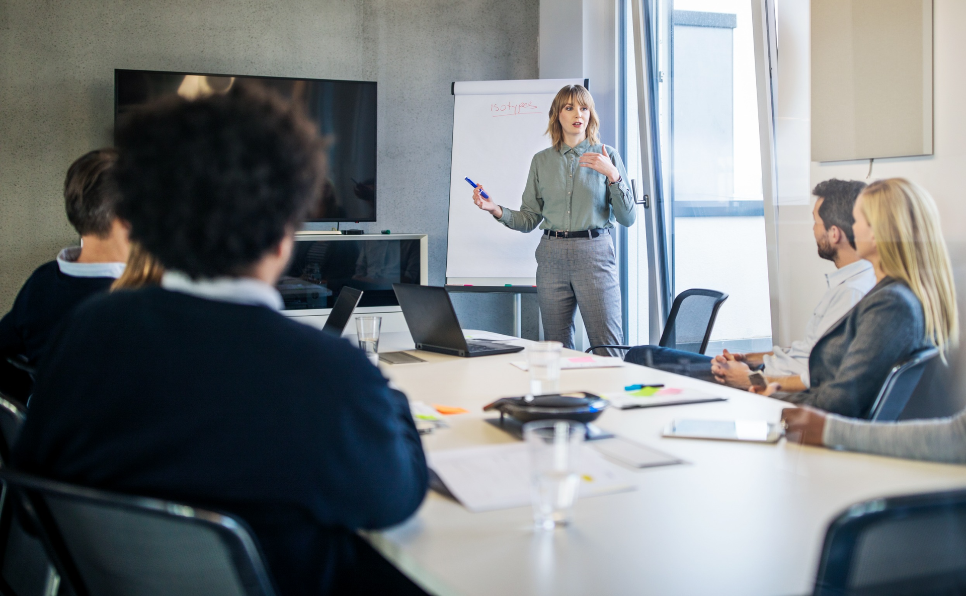 A woman is giving a presentation to a group of people in a conference room.