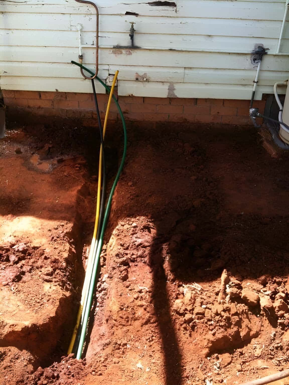 A Hose Is Laying In The Dirt In Front Of A House — Nudges Plumbing In Coonabarabran, NSW