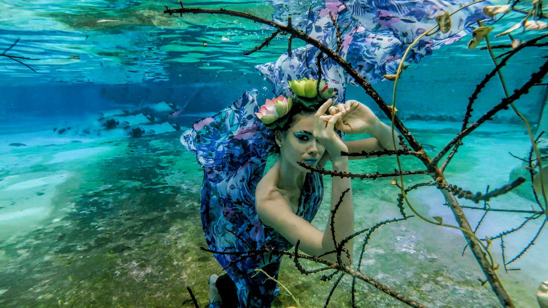 A woman is underwater with a flower crown on her head