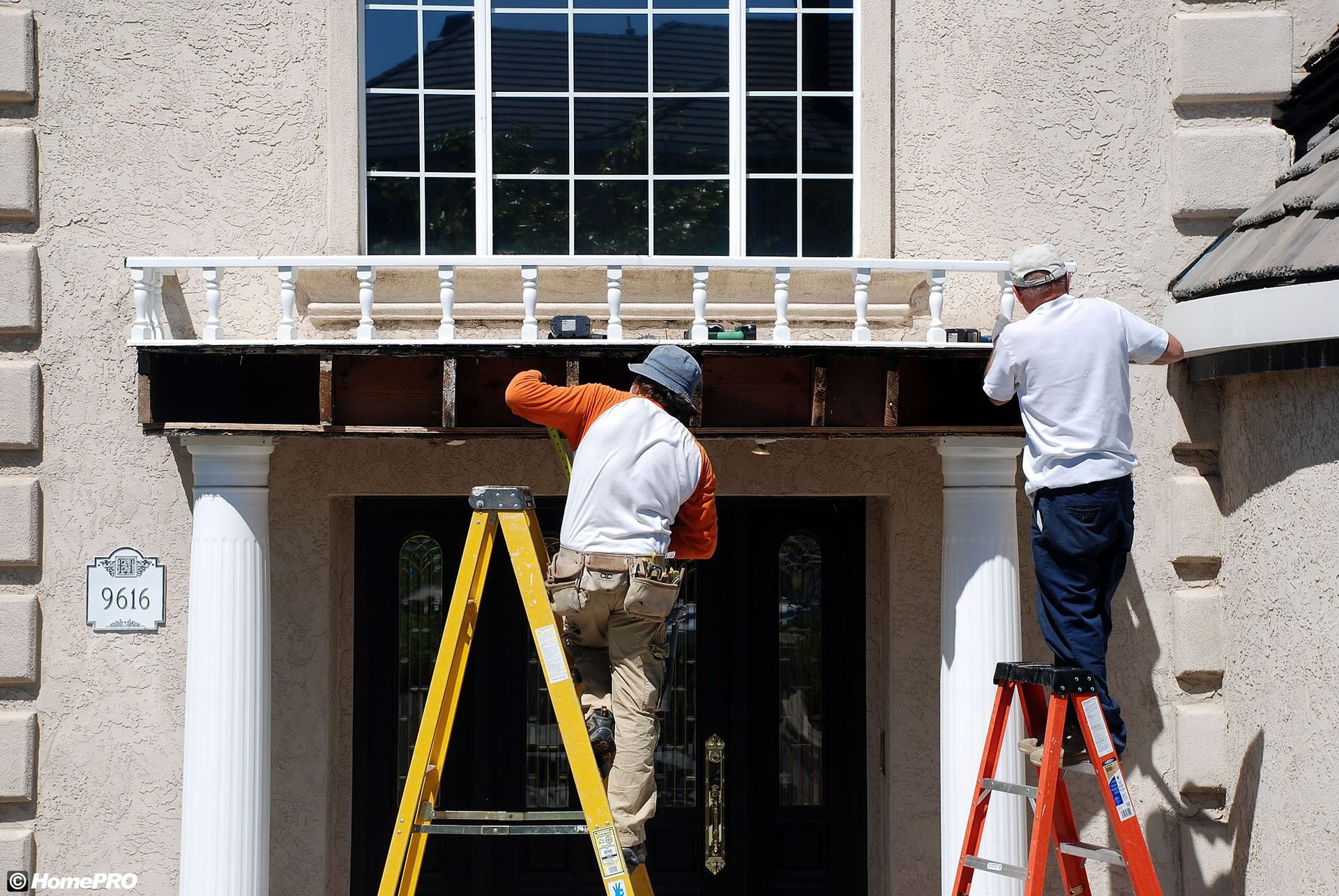 two men are painting the side of a house