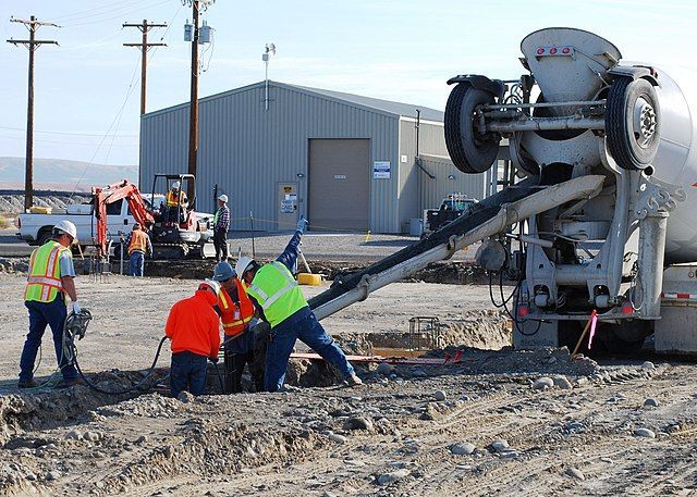 Workers shoveling concrete out of a concrete truck for a new foundation