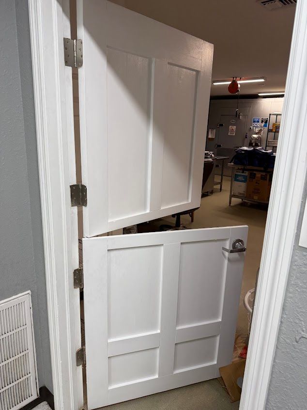 White, split door, ajar, partially obstructing a hallway.