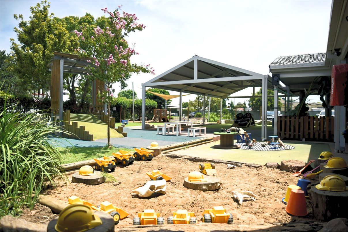 A sandbox filled with toys and hard hats in a playground.