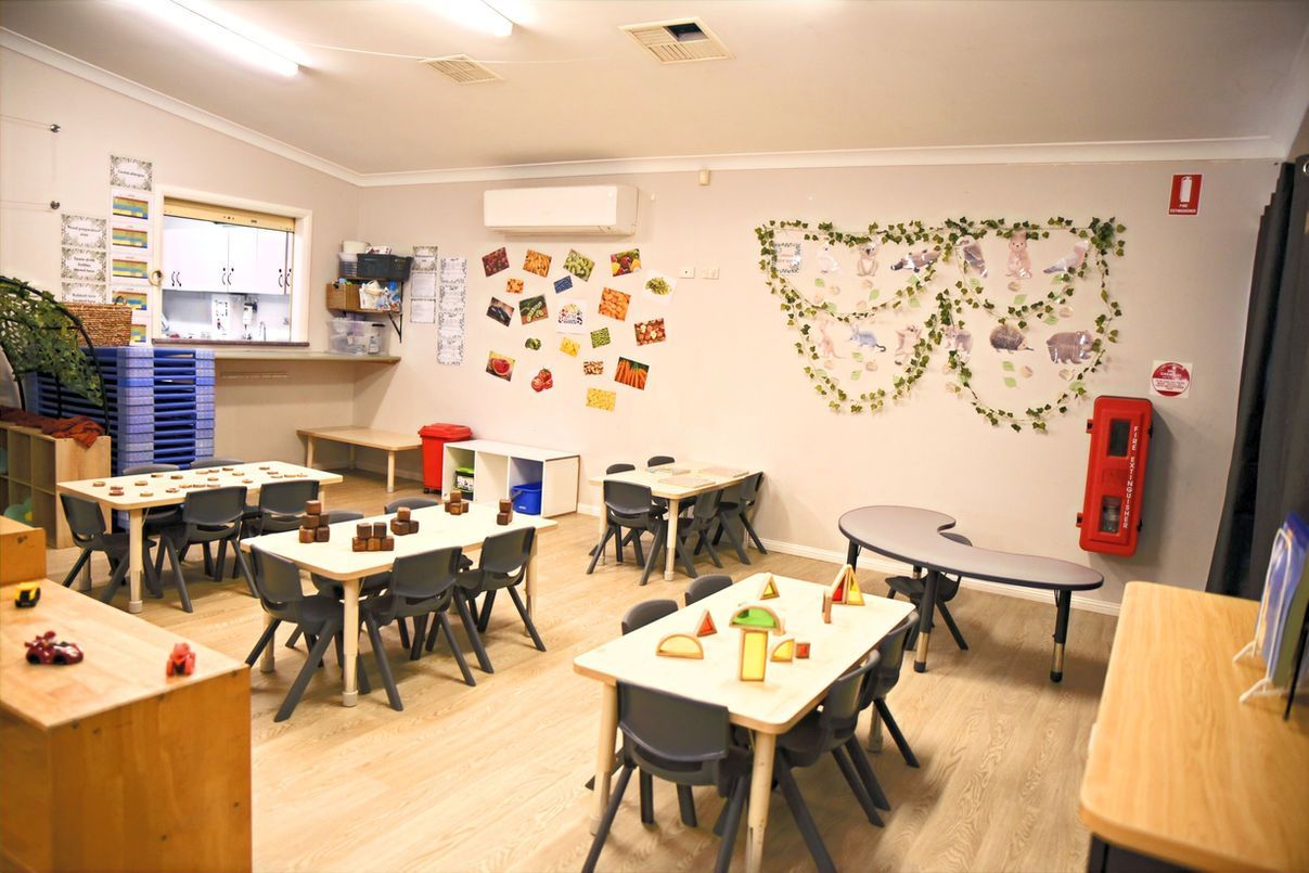A classroom with tables and chairs and a butterfly on the wall.