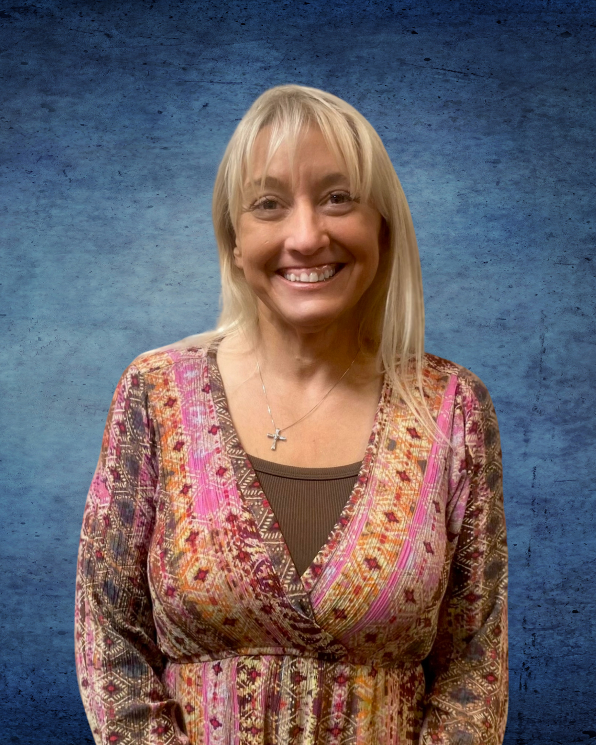 A woman in a purple scrub top is smiling for the camera