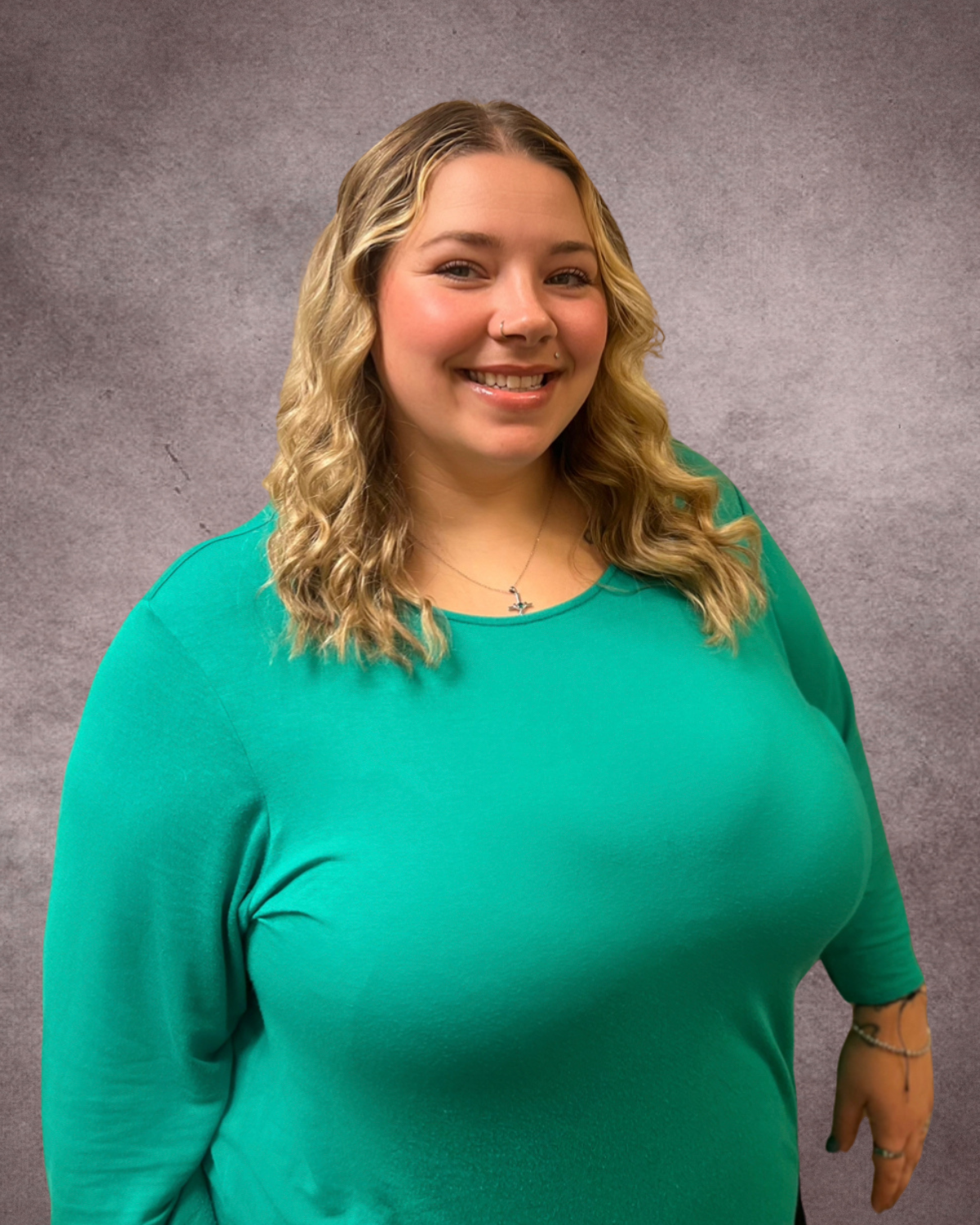 A woman in a purple scrub top is smiling for the camera