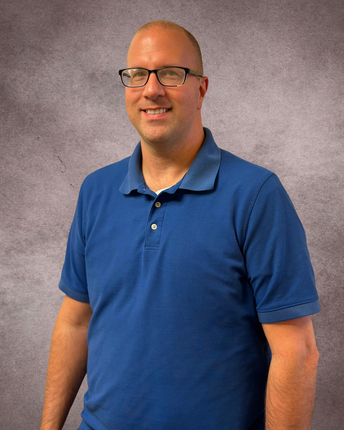 A man wearing scrubs and glasses is smiling for the camera