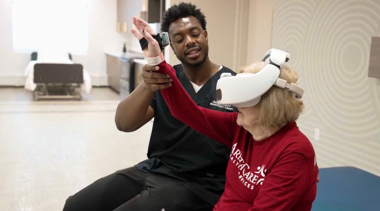 A man is helping a woman wearing a virtual reality headset.