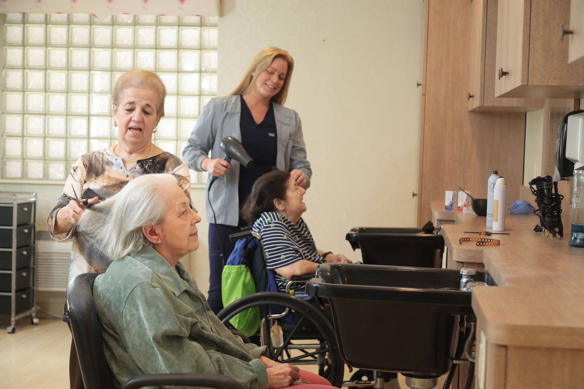 A woman is blow drying another woman 's hair in a salon.