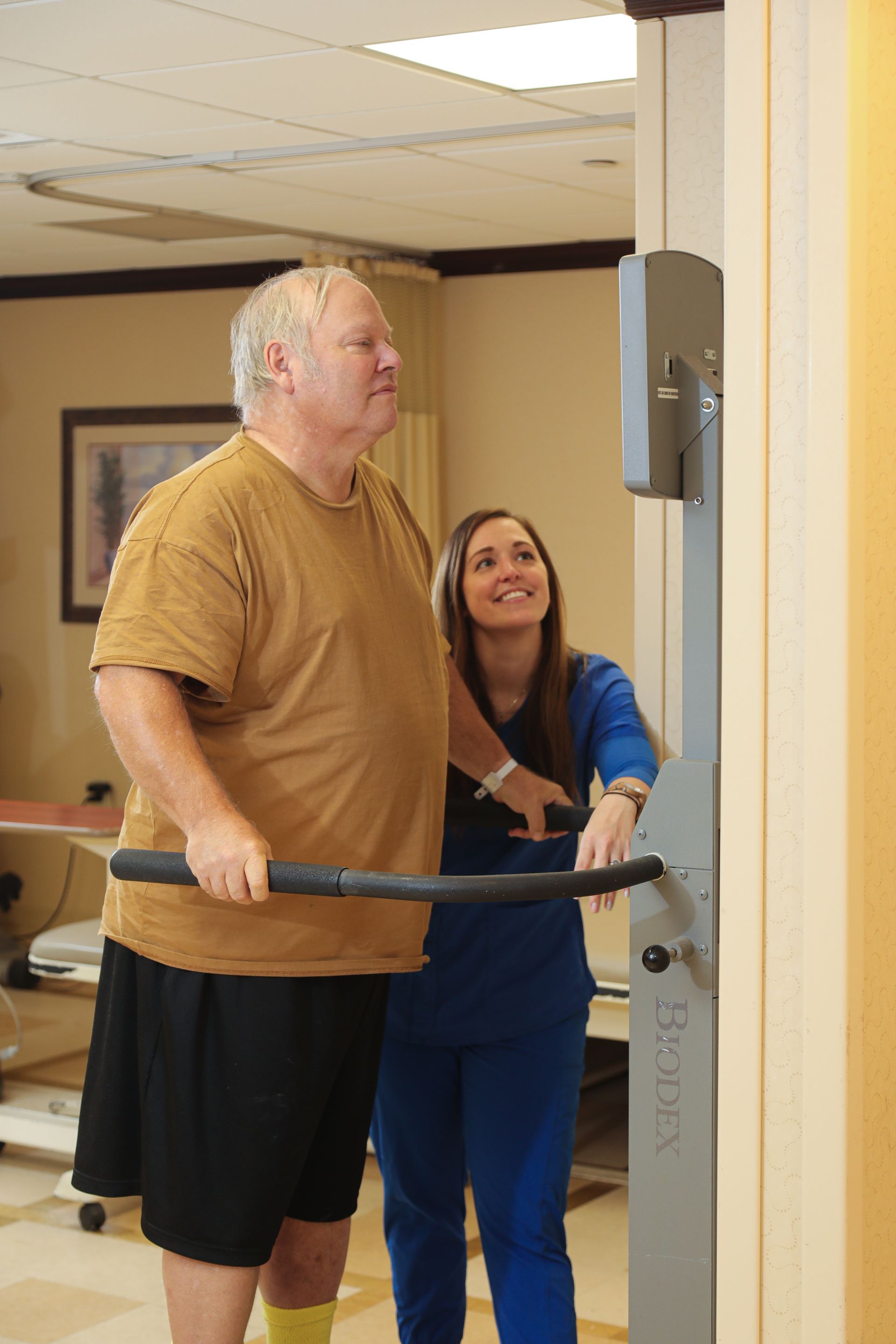 A man is being helped by a nurse to walk on a machine.