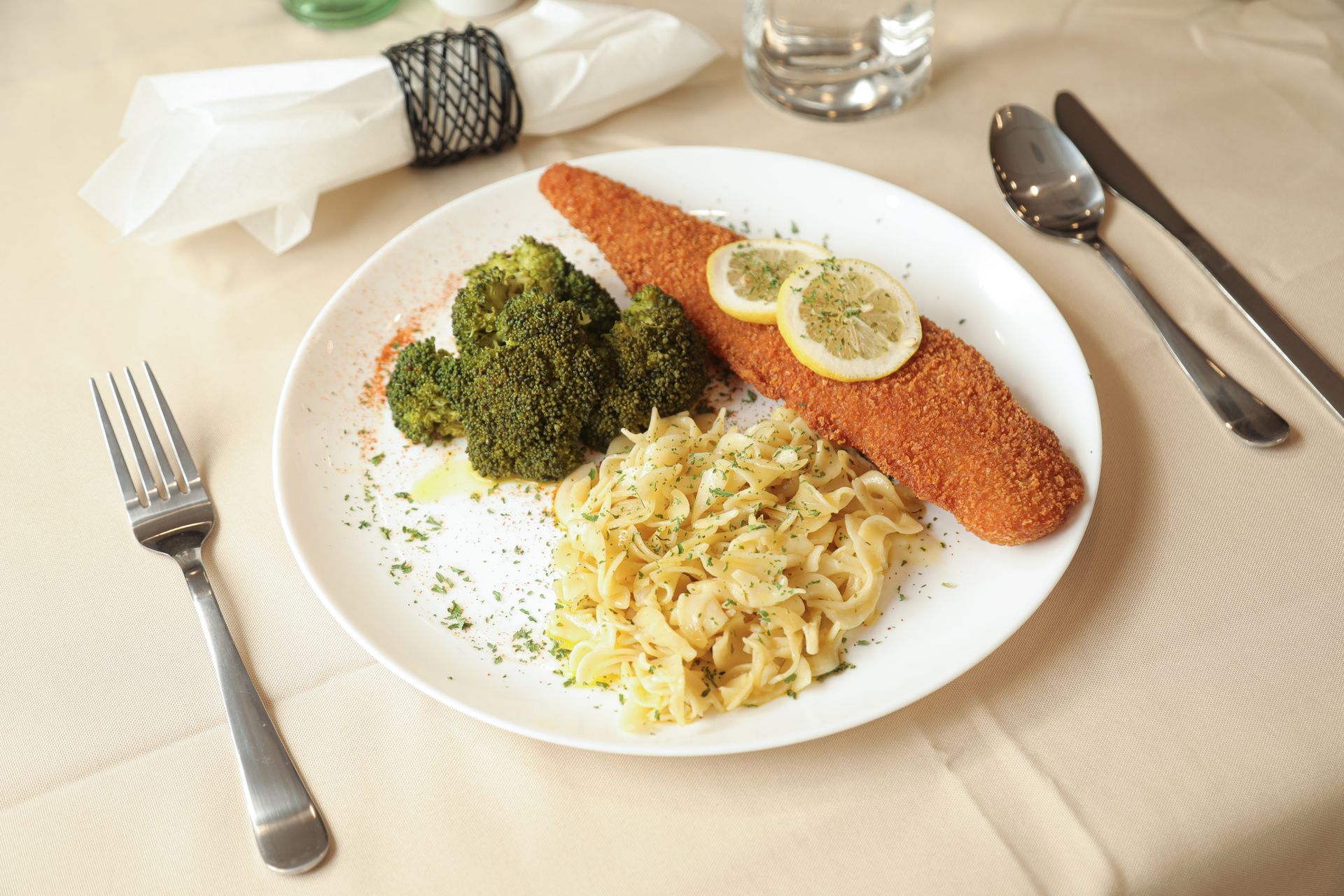A plate of food with broccoli and noodles on a table.