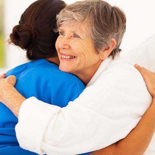 A woman in a blue shirt is hugging another woman in a white robe