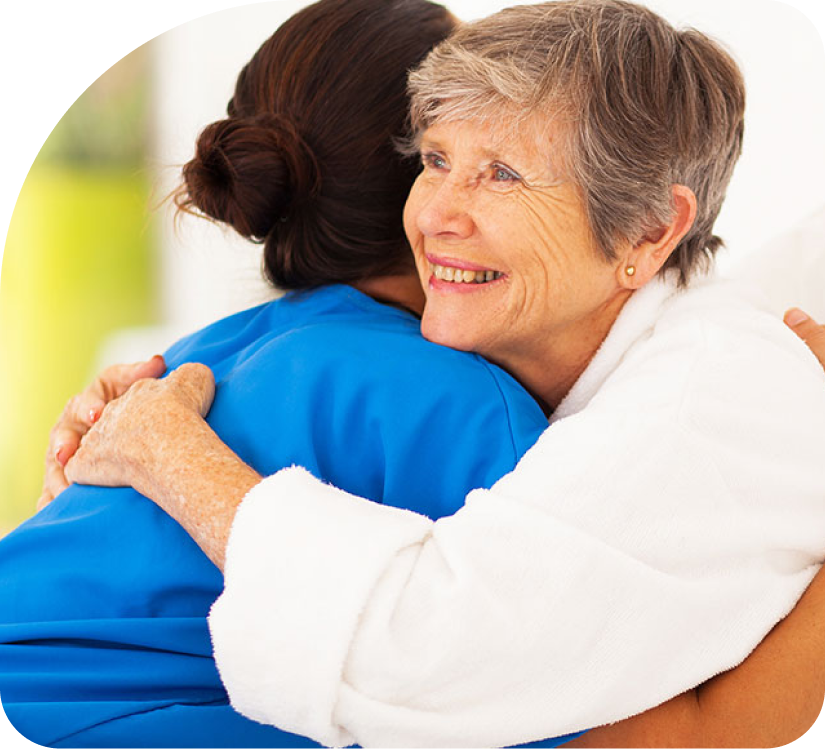 A woman in a blue shirt is hugging an older woman in a white shirt