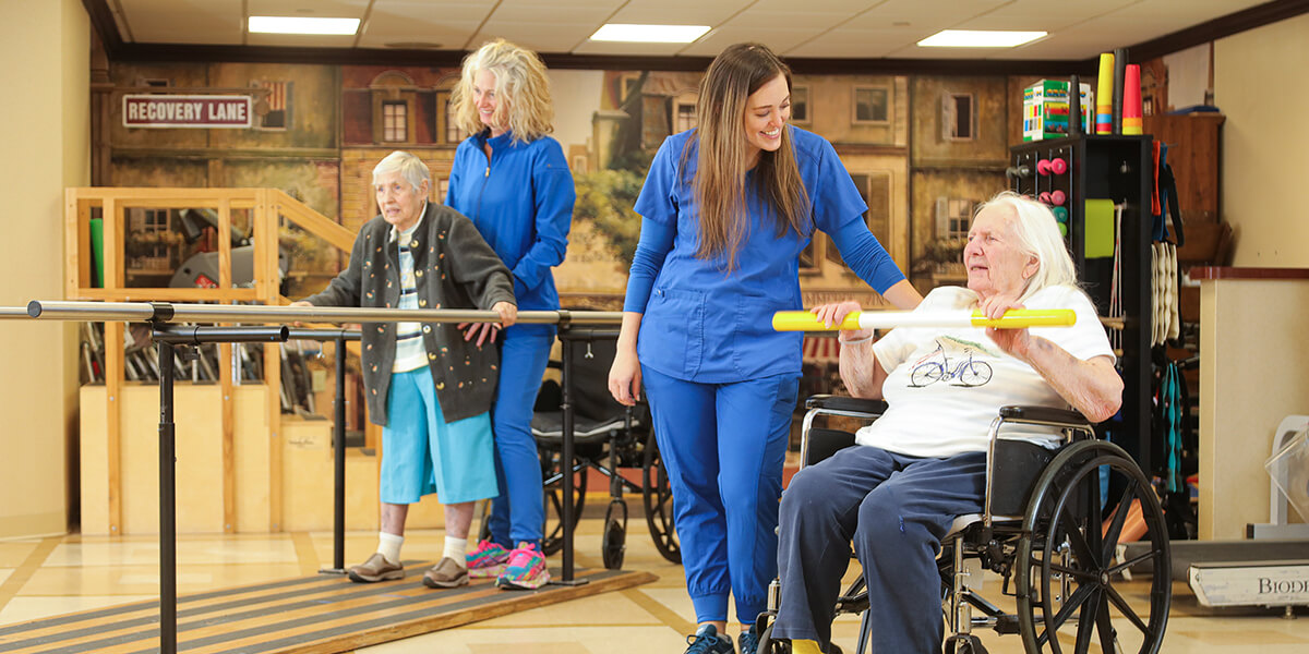 A woman in a wheelchair is being helped by two nurses.