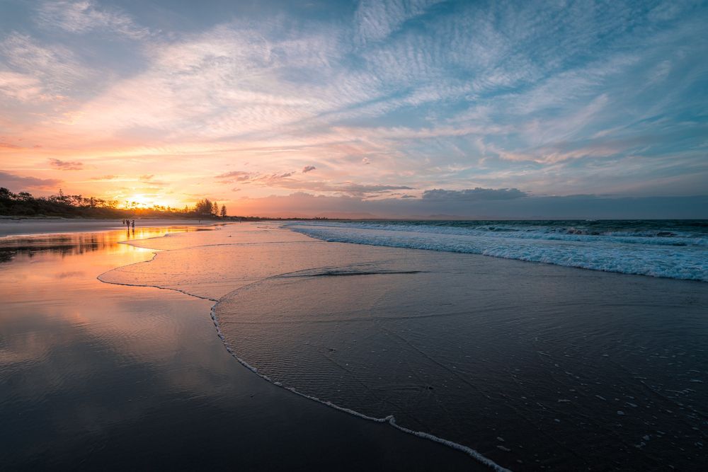 A Beach With A Sunset In The Background And Waves Crashing On The Shore — Tweed Byron Recycling In Byron Bay, NSW