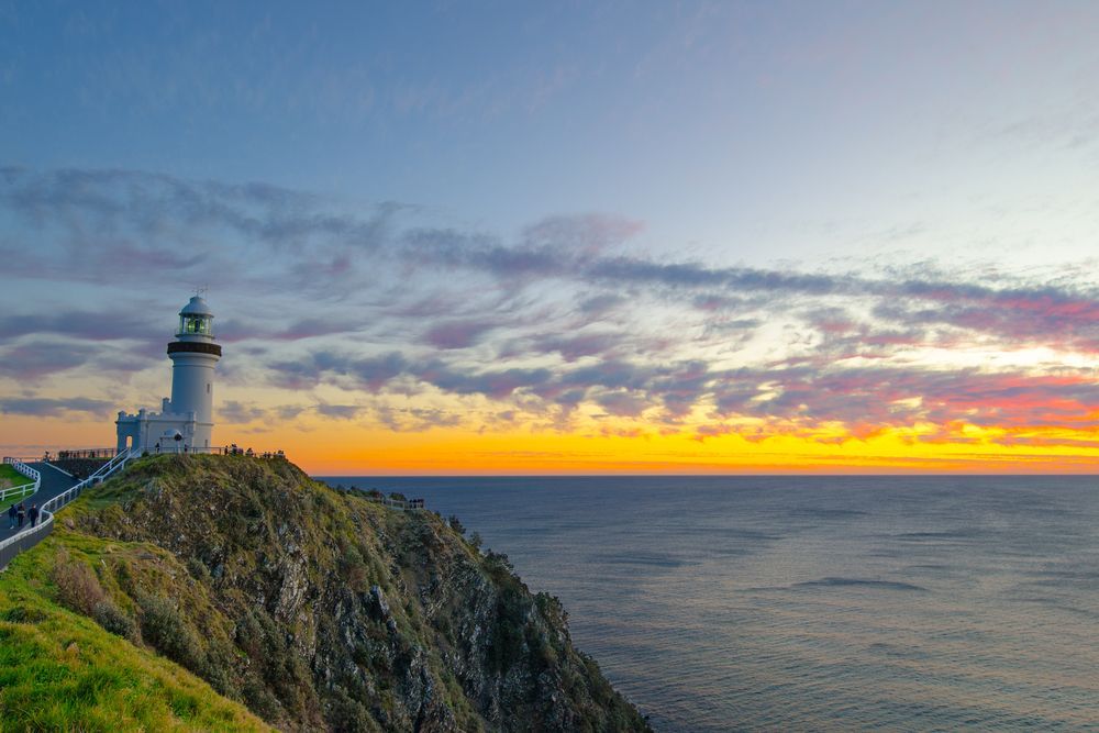 A Lighthouse On Top Of A Cliff Overlooking The Ocean At Sunset — Tweed Byron Recycling In Byron Bay, NSW
