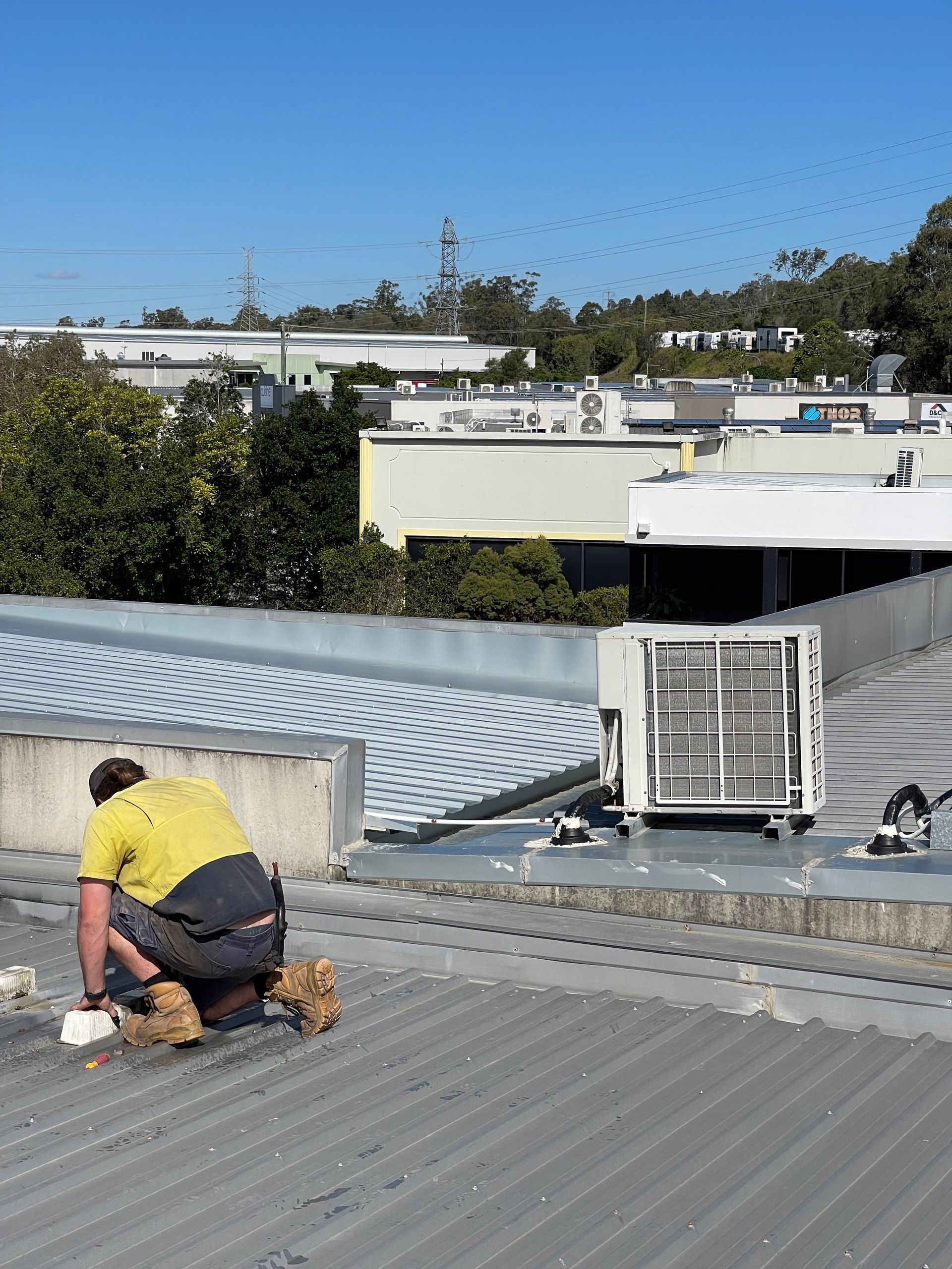 A Man Is Working On The Roof Of A Building — Tweed Byron Recycling In Tweed Heads, NSW