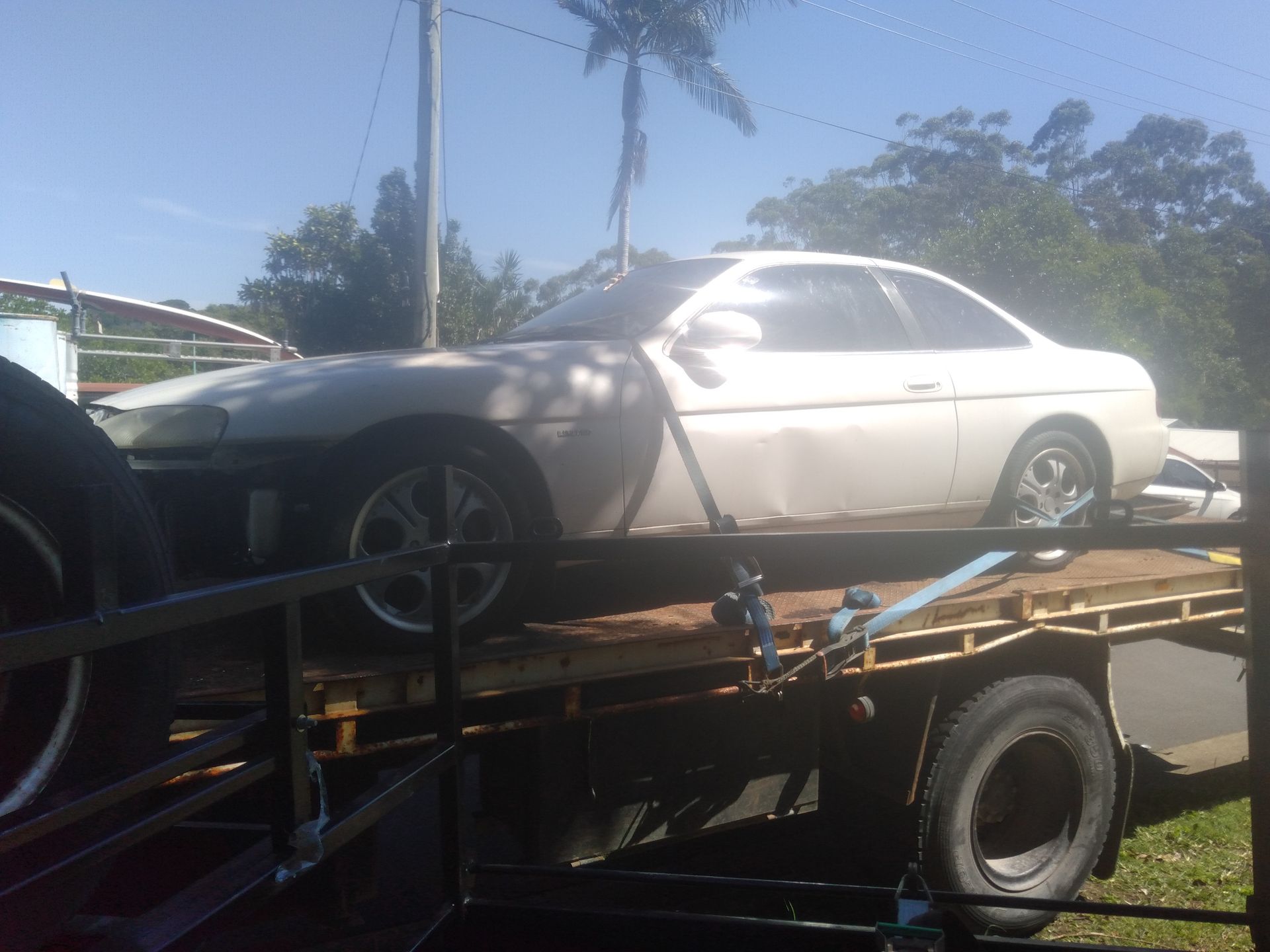 A White Car Is Sitting On Top Of A Tow Truck — Tweed Byron Recycling In Ballina, NSW