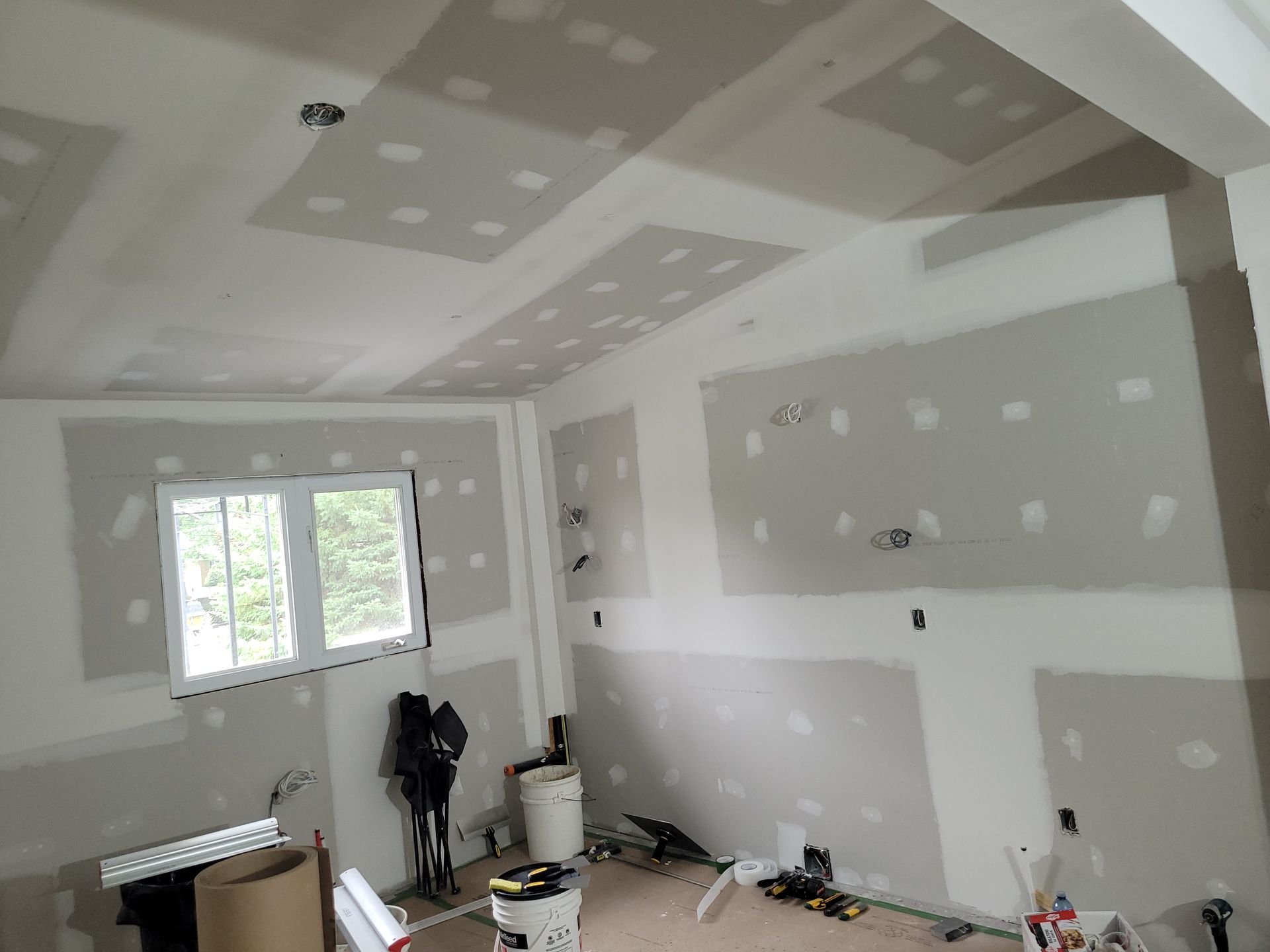 Une pièce en cours de rénovation avec des cloisons sèches et une fenêtre.