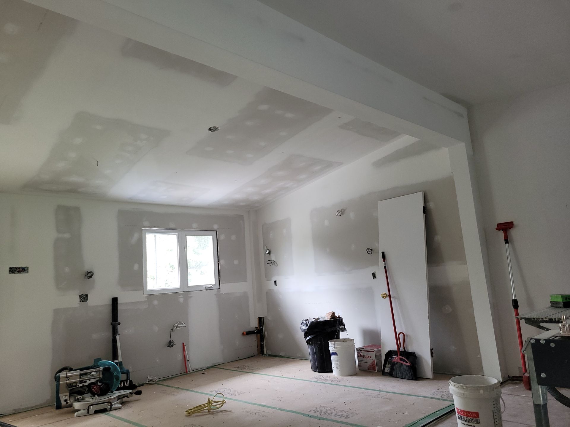 Une pièce en cours de rénovation avec des cloisons sèches sur les murs et le plafond.