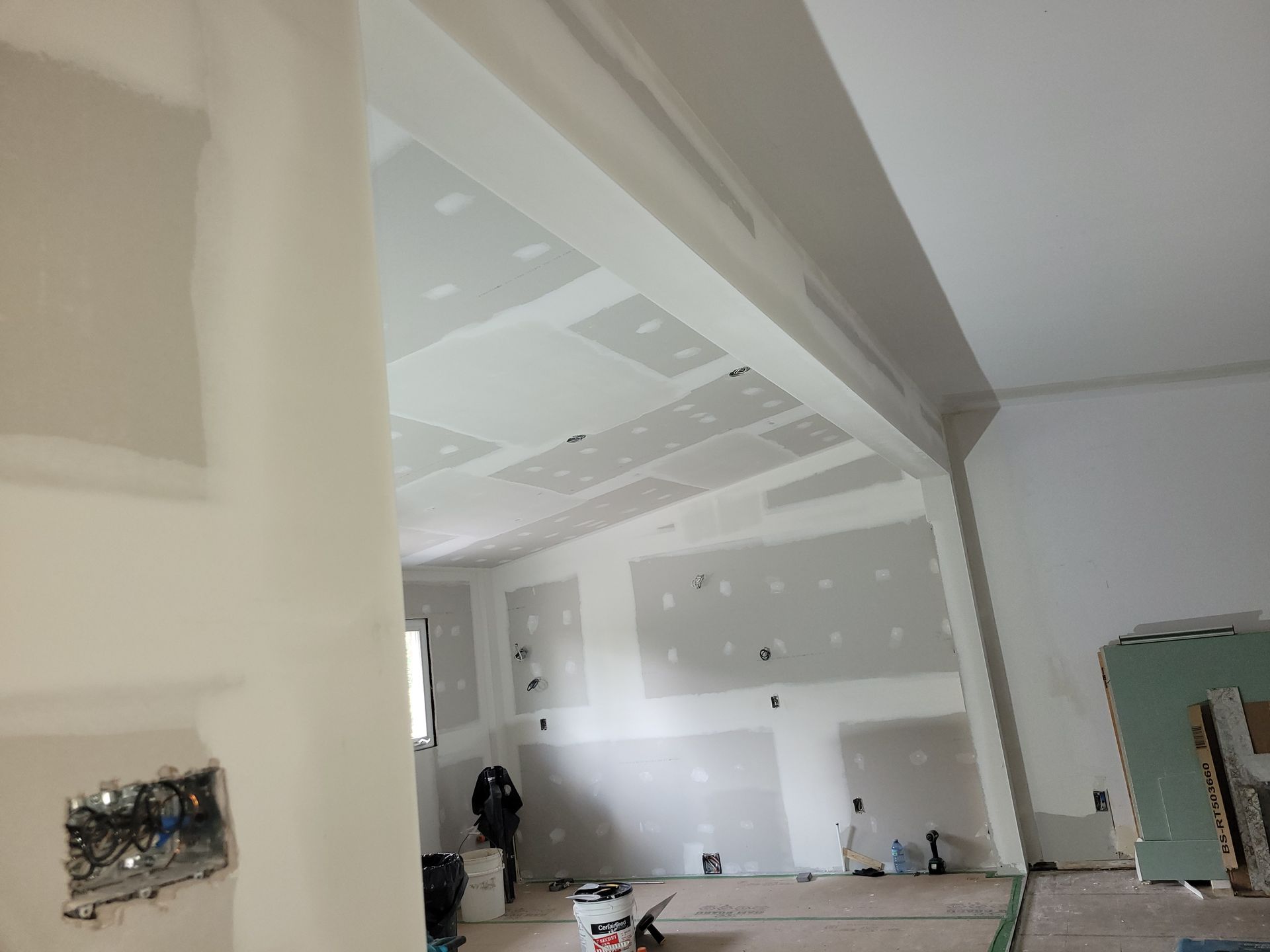 Une pièce en cours de rénovation avec des cloisons sèches sur les murs et le plafond.