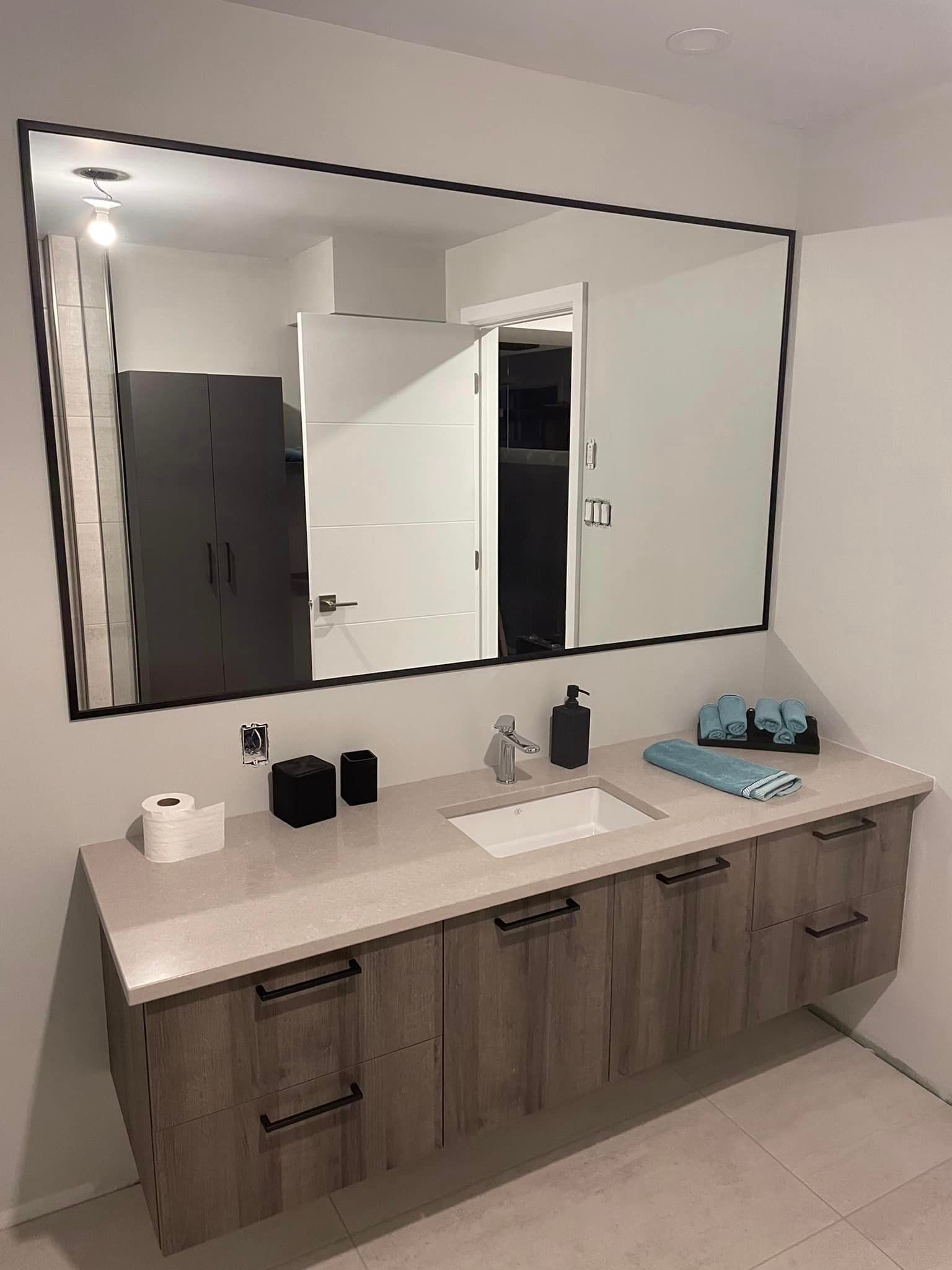 Une salle de bain avec un grand miroir et un lavabo.