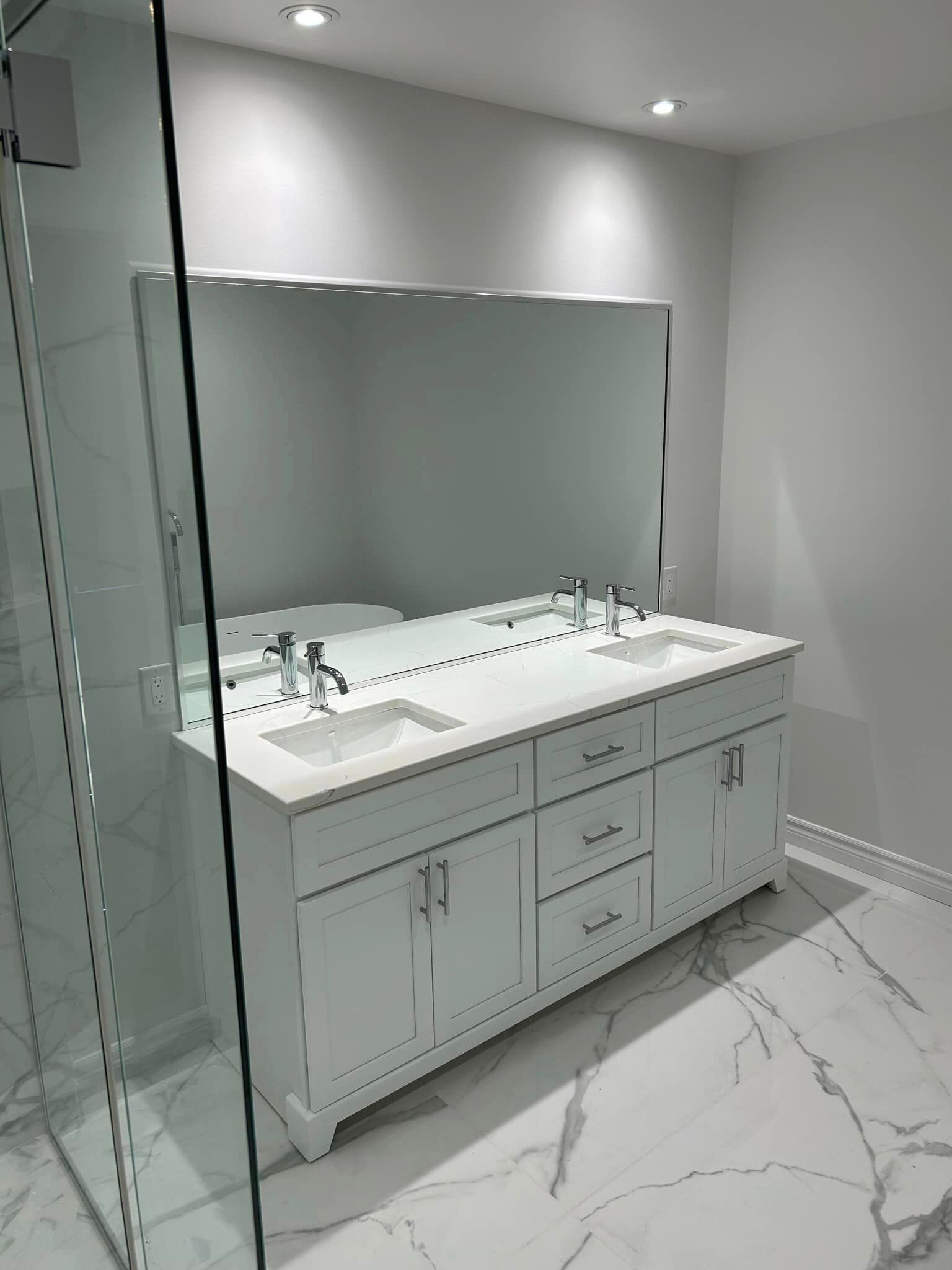 Une salle de bain avec deux vasques, un grand miroir et une douche à l'italienne.