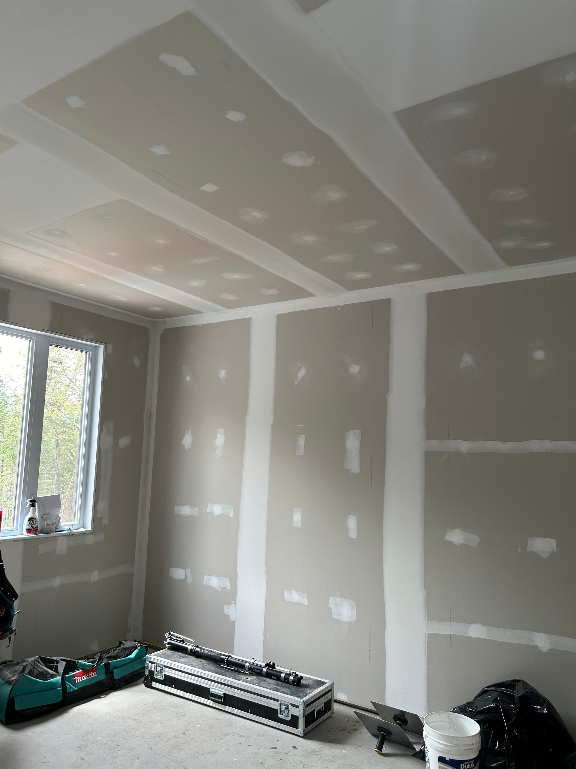 Une pièce avec beaucoup de cloisons sèches et une fenêtre.