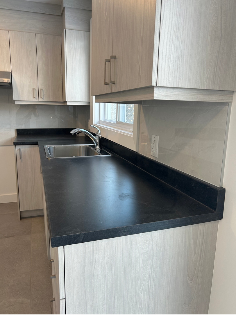 Une cuisine avec des armoires blanches et un comptoir noir.