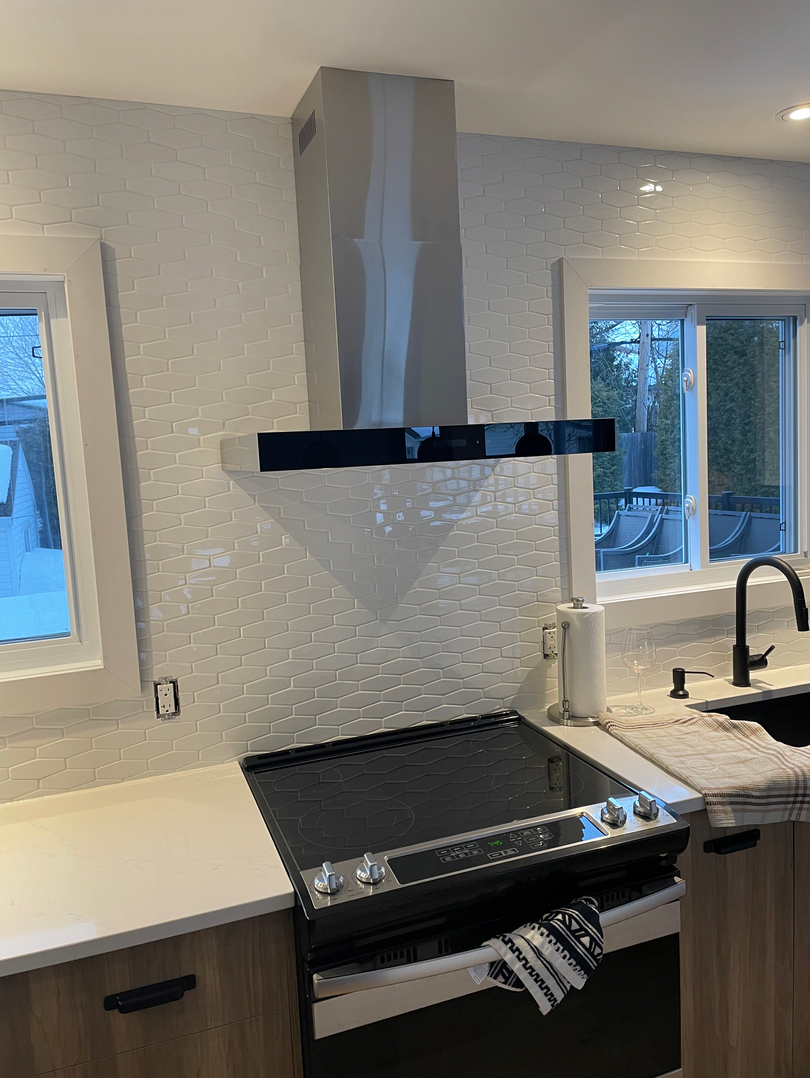 Une cuisine avec une cuisinière, un évier et une fenêtre.