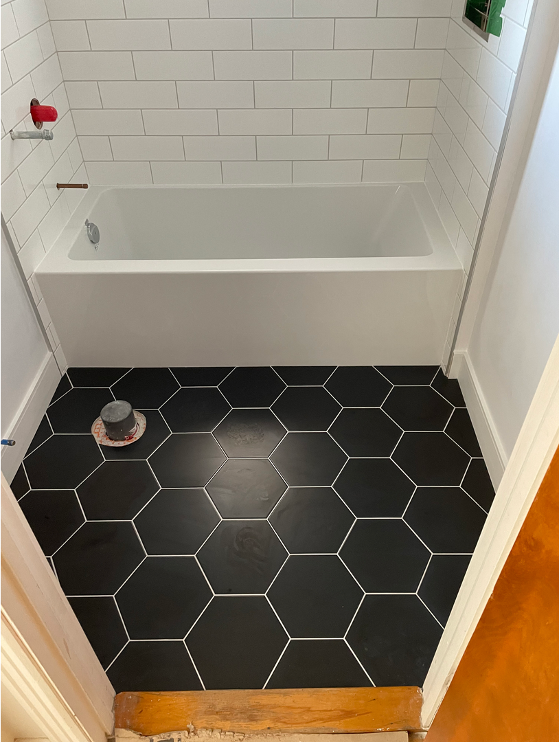 Une salle de bain avec baignoire et sol en carrelage noir