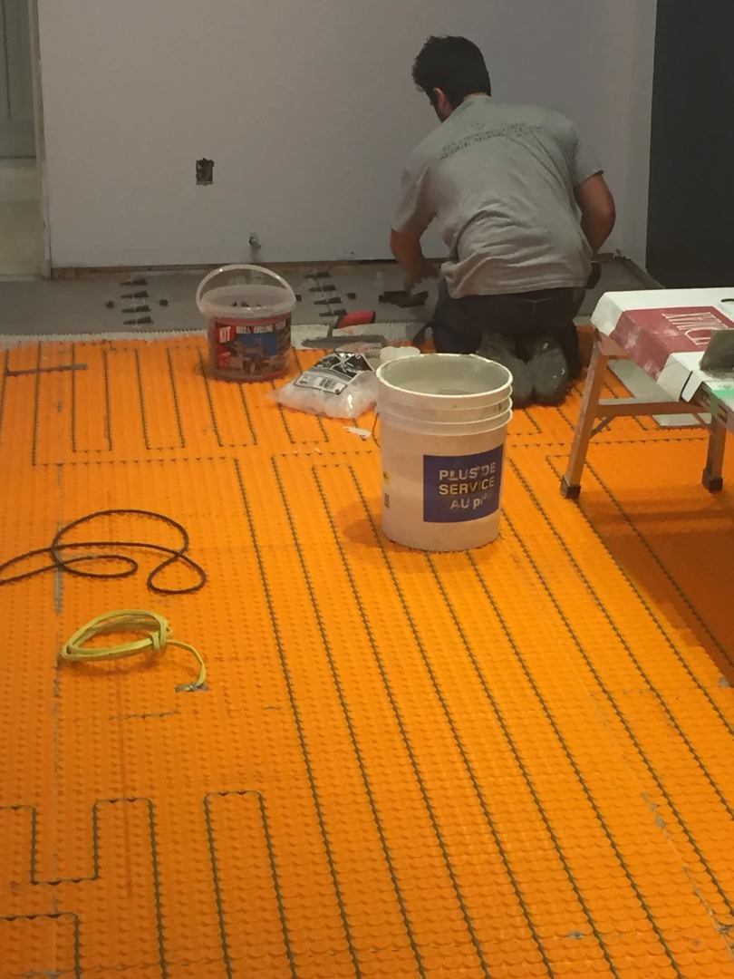 Un homme est à genoux sur le sol avec un seau sur lequel est écrit 