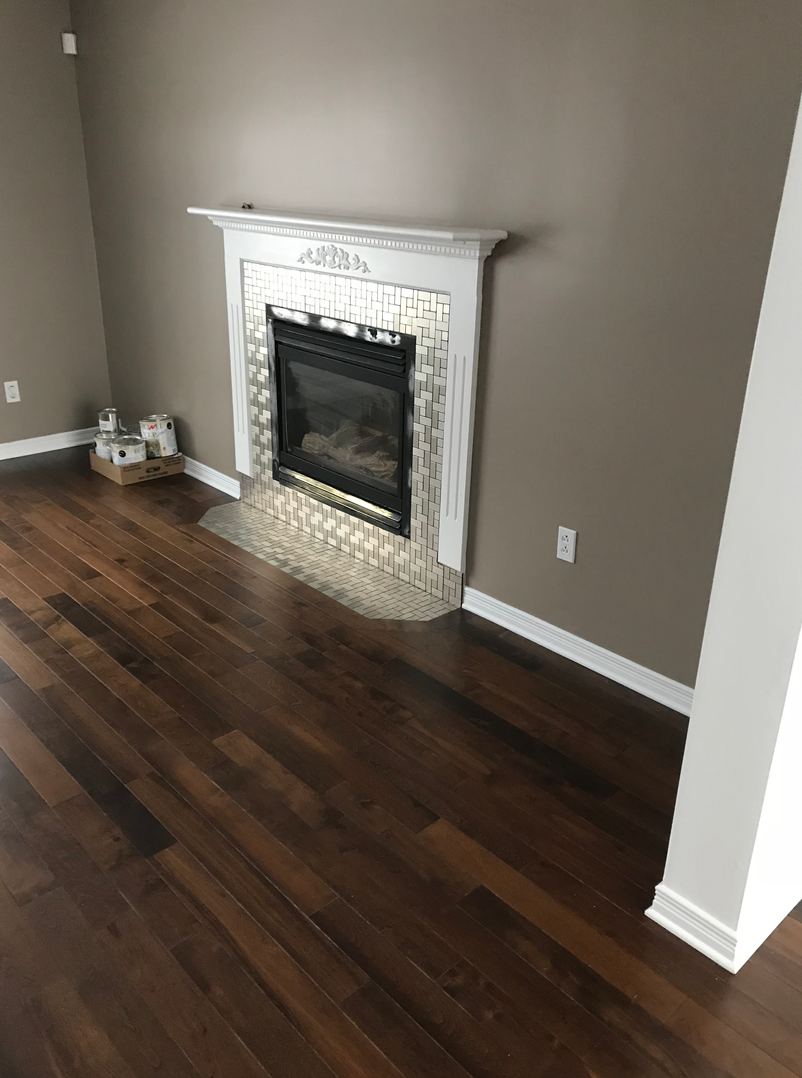 Un salon avec parquet et cheminée.